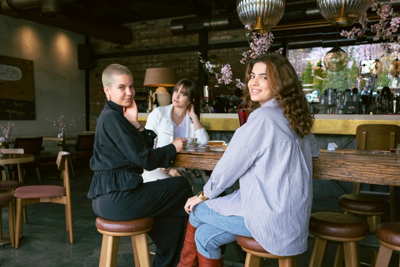 women sitting at a table together, drinking a glass of wine