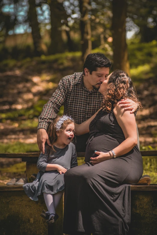 a family kissing and sitting together on a wooden bench