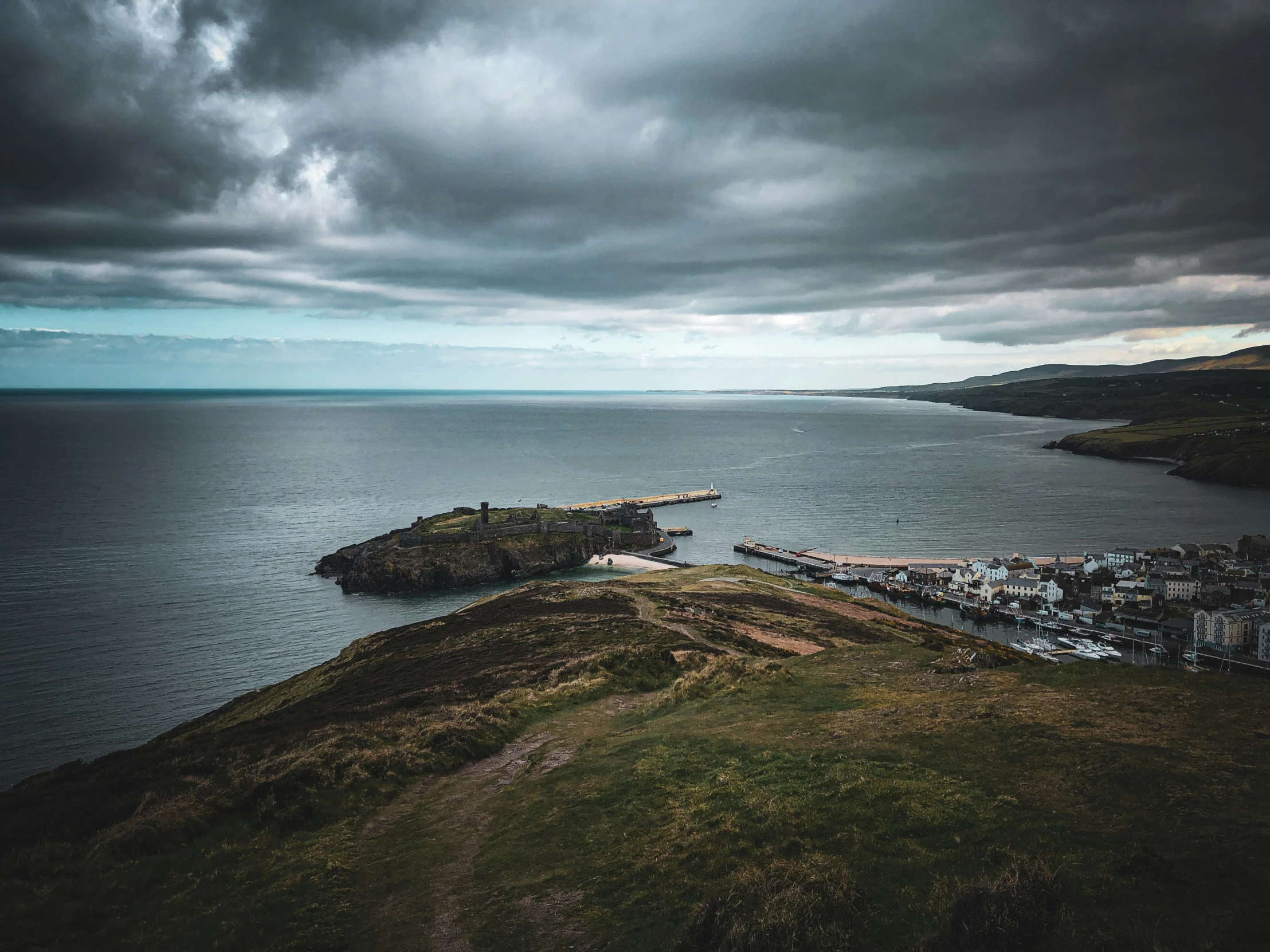 a storm filled sky over the ocean and small town