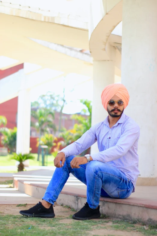 a man with a turban sitting on some concrete