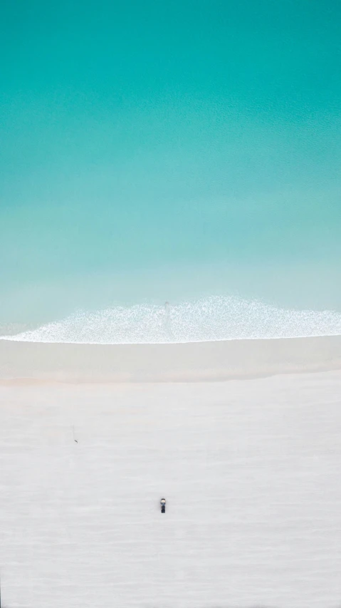 a lone figure on a beach with the ocean in the background