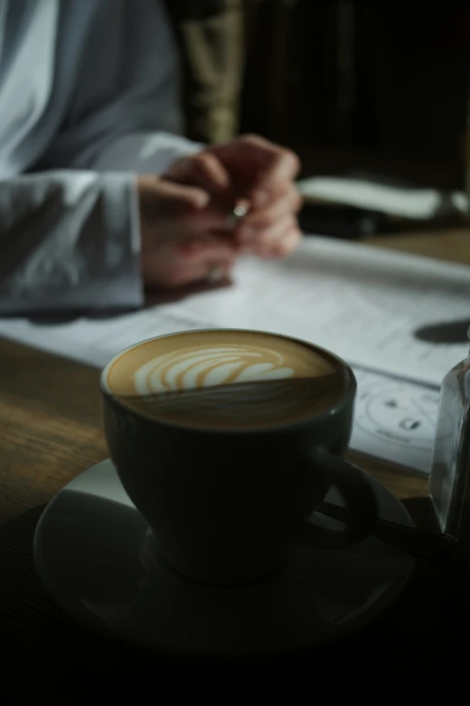 a cappuccino sits on a white plate and holds a persons hand