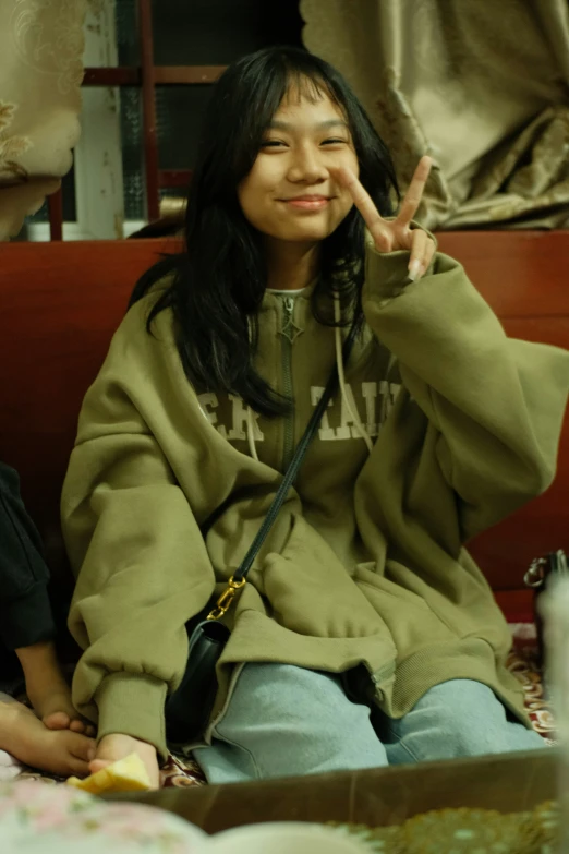 a woman sitting down holding up a peace sign