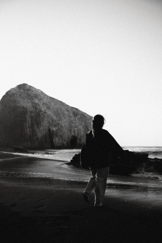 black and white pograph of man walking on beach