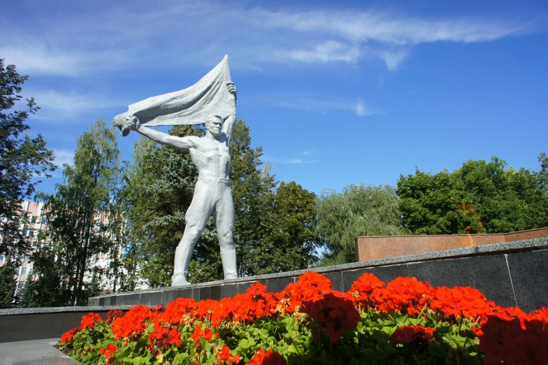 flowers grow in the foreground near a statue