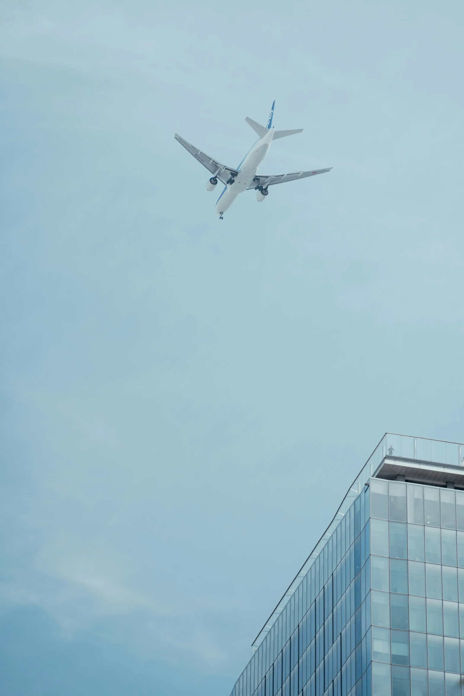 large airplane flying over the head of an office building