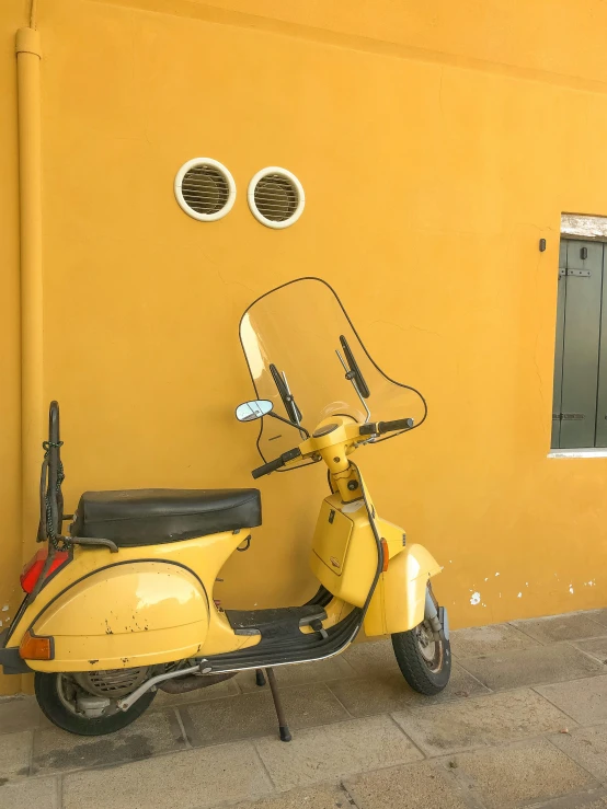 a yellow moped parked next to a building