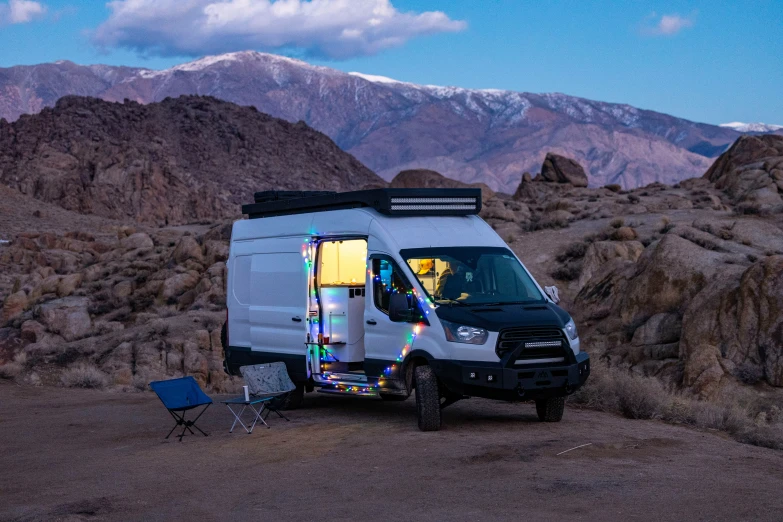 an enclosed van with a canopy attached parked in front of mountains