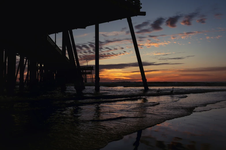 the sun is setting at the beach and it's silhouettes the water