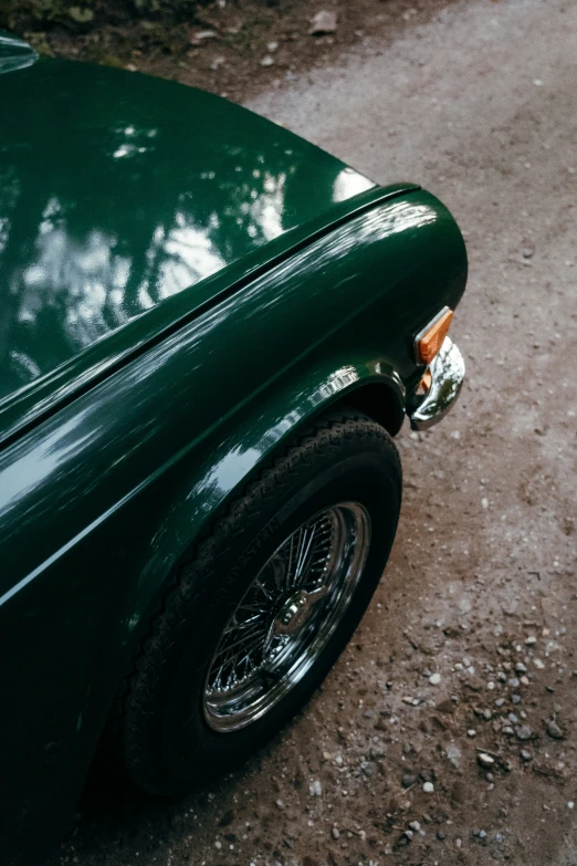 the rear end of a parked green car on dirt