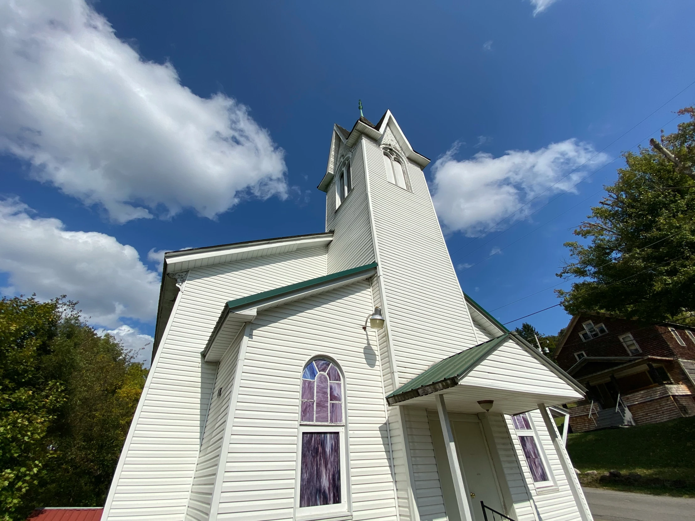 a small church with trees and a blue sky in the background