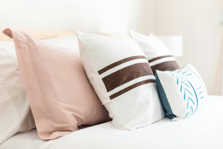 a bed with white pillows and two brown and pink pillows