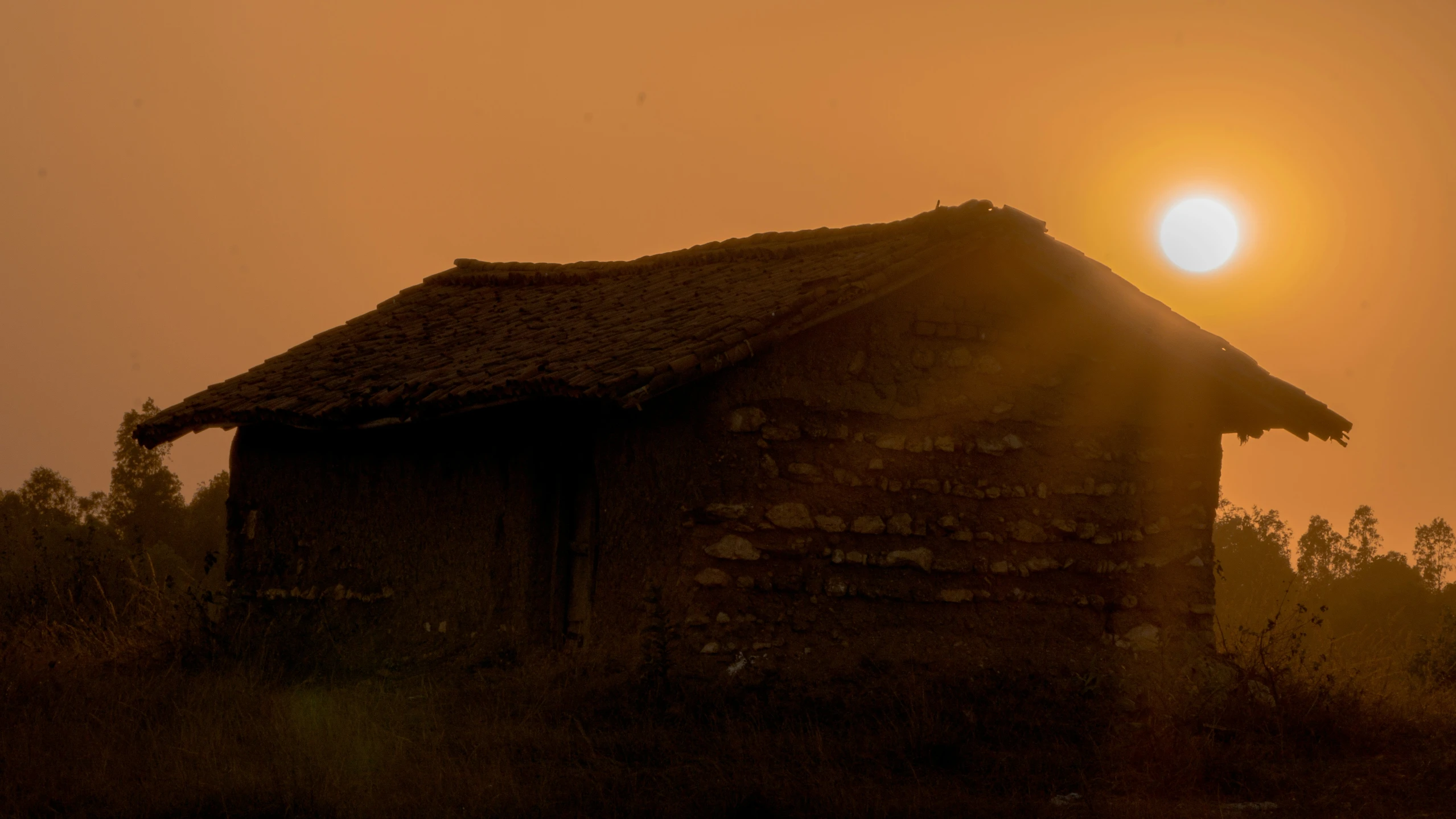 the sun setting over the building behind the fence