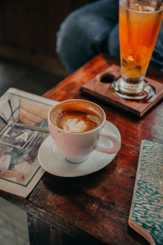 a cup of coffee on a saucer sits in front of a glass of liquid