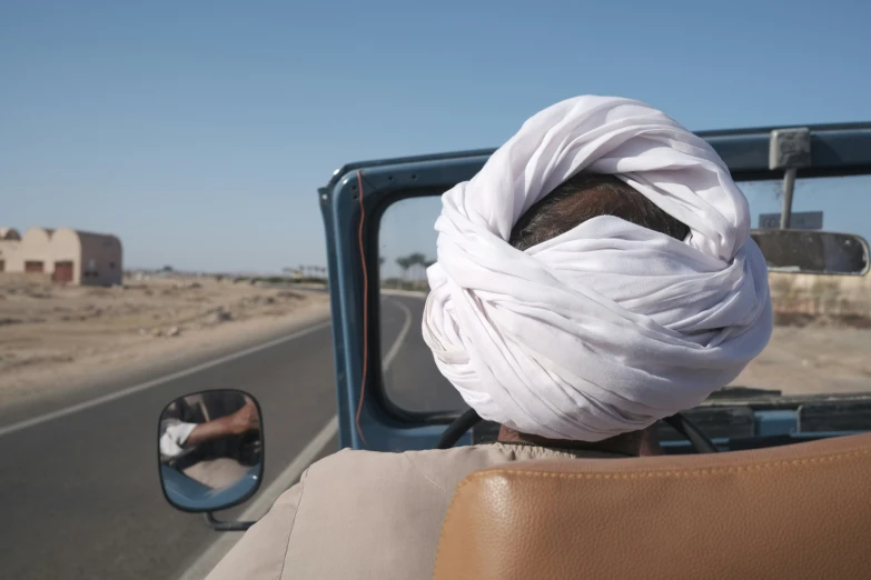 a man with a turban is on his head and in the car