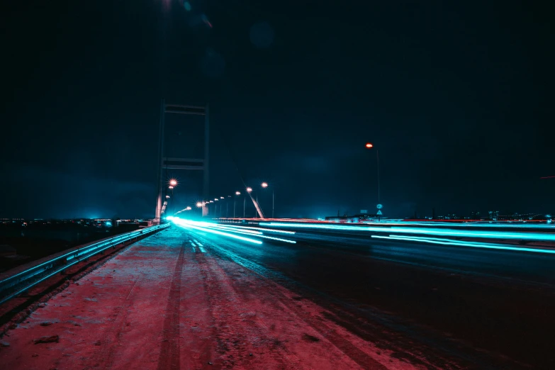 the light trails are blurred as cars drive over a snowy bridge