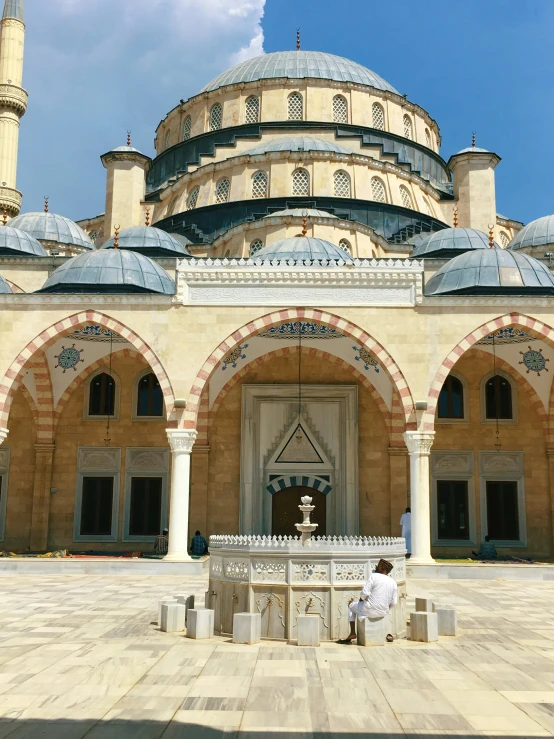 a mosque with a circular building with arched pillars and domed roof