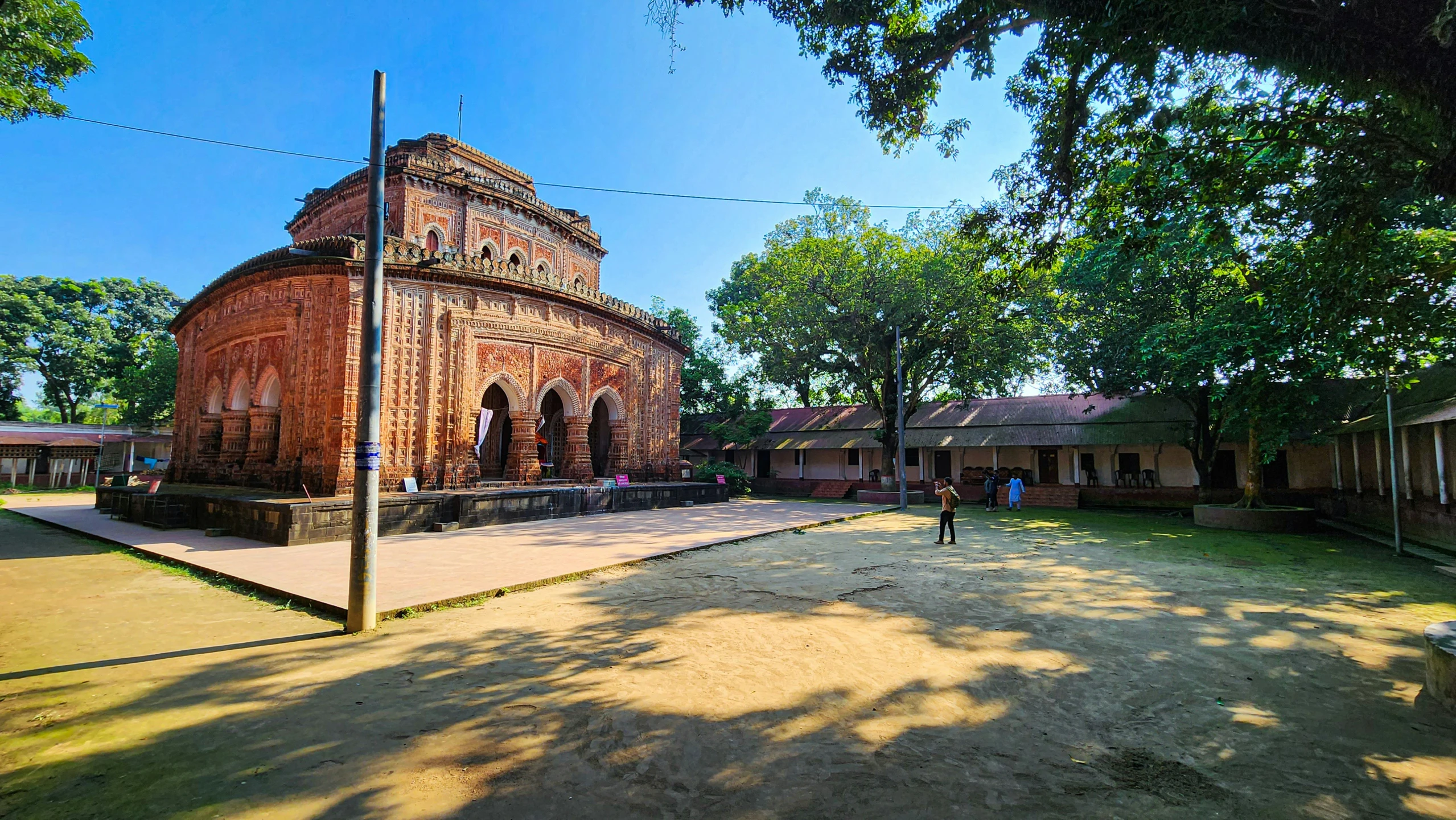 a brick building with trees and people walking around