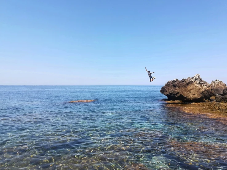 the person is sky diving off a rocky shore