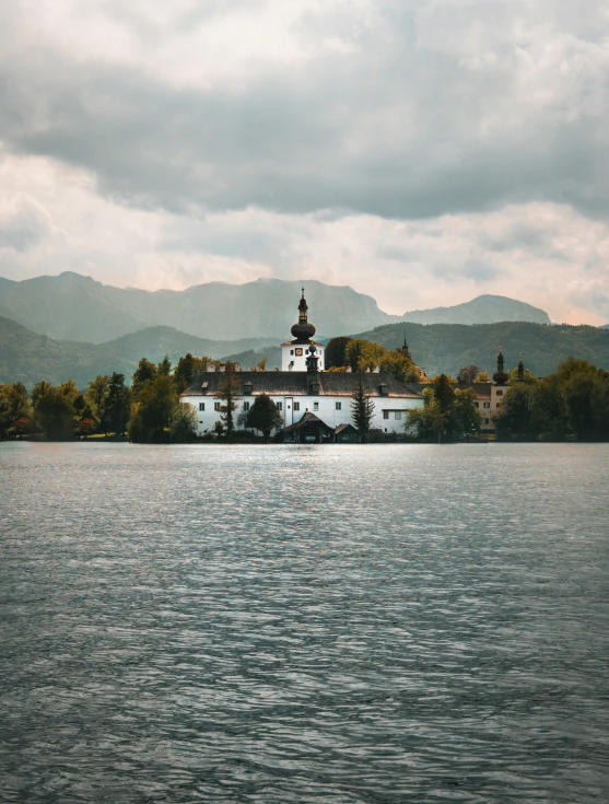 a white house near some trees and mountains