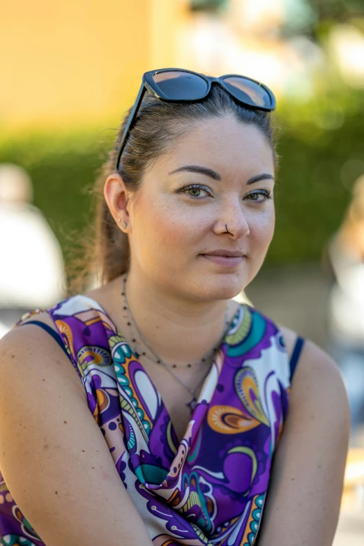 a woman with sunglasses on sits and smiles