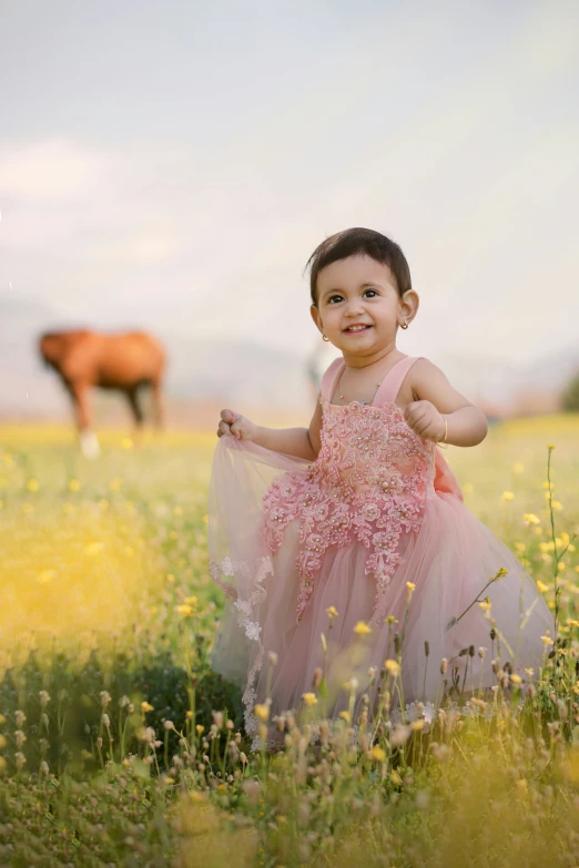 a little girl is smiling for the camera in front of a field