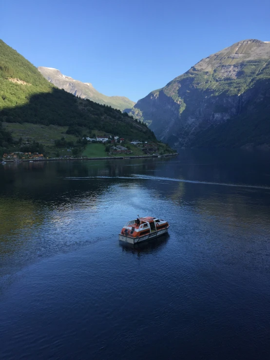 a lake surrounded by mountains, with a small boat on it