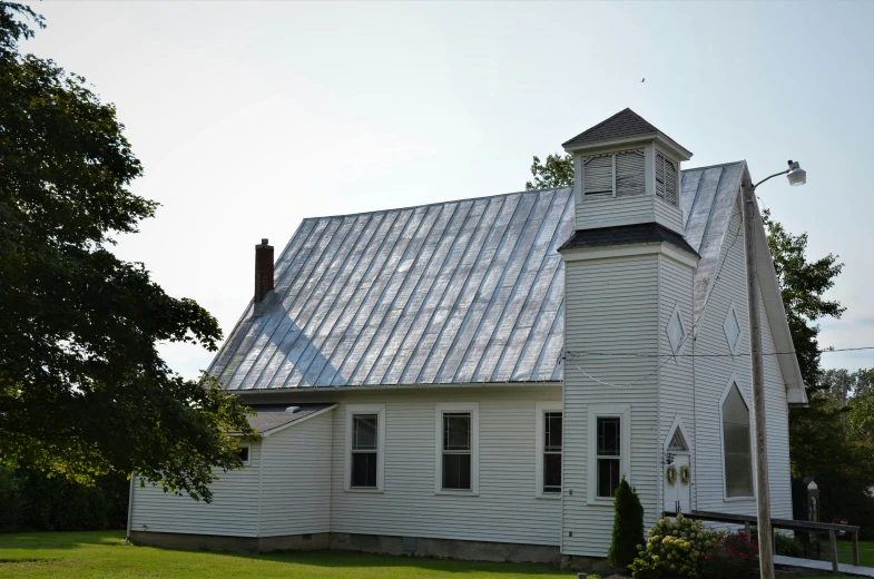 this small white church with two towers is near some trees