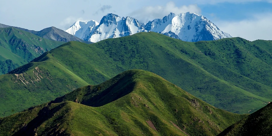 a majestic green mountain range with a snow covered mountain range