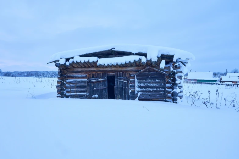 an old log cabin stands in the snow