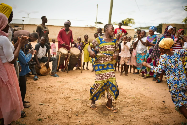 a man dances with a drum in front of a group of people