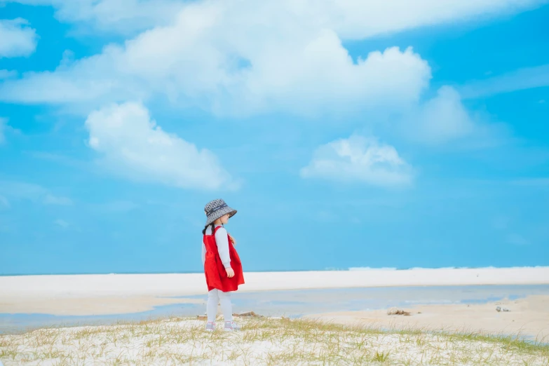 a woman standing on a beach with her hat on