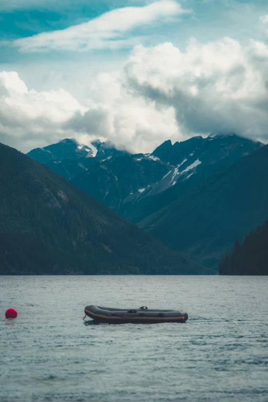 a dingling boat is floating on a river in a mountainous area