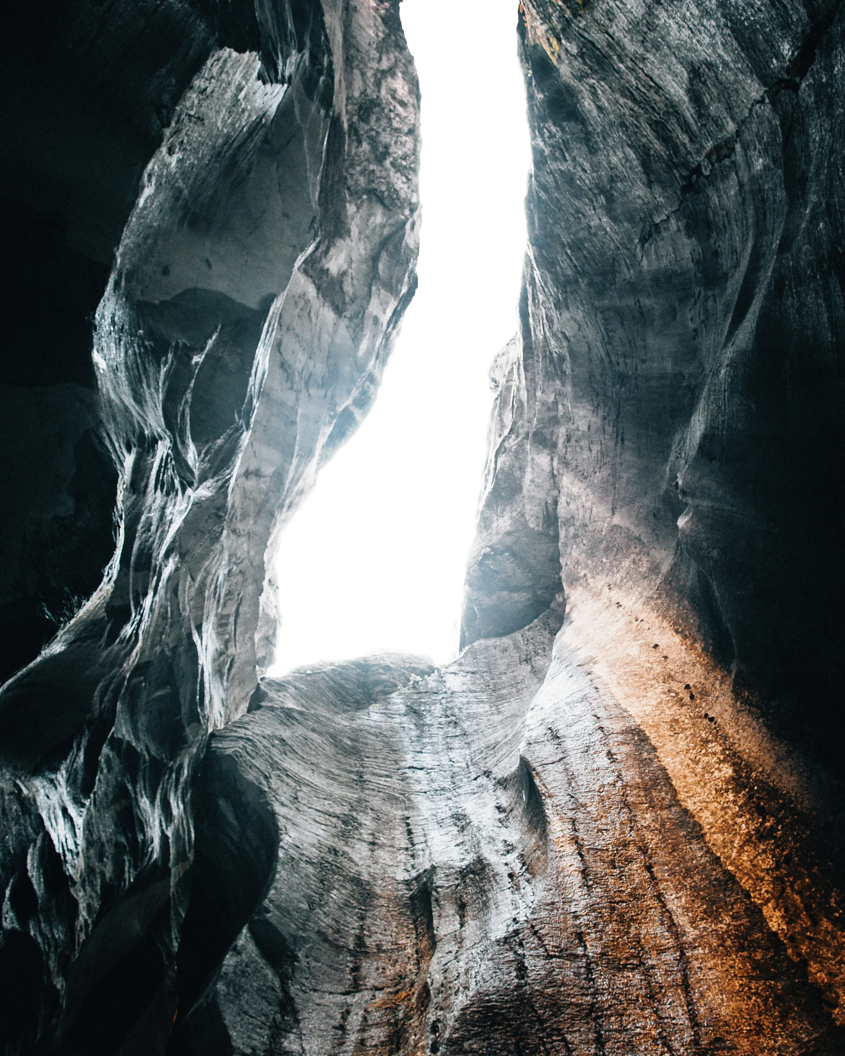 two faces are seen through the rocks near a body of water