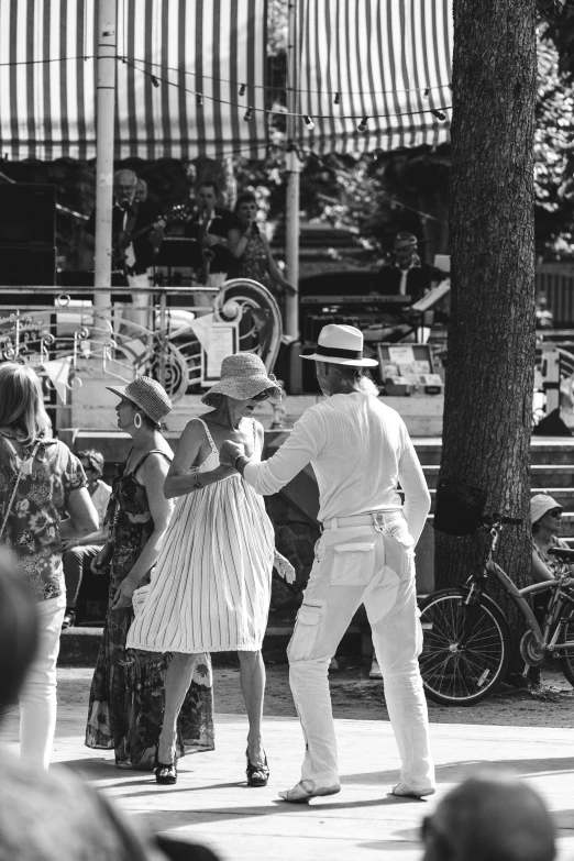 two people dance and one man sits on a bench