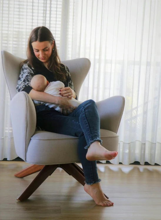 the woman is sitting down while holding the baby