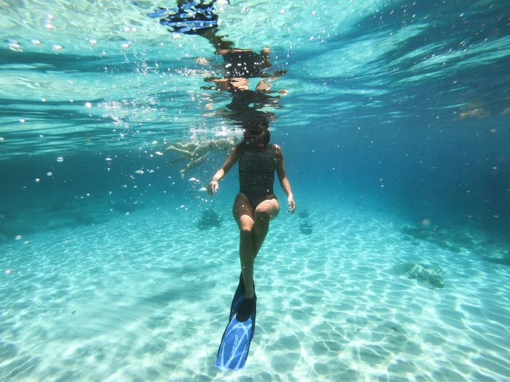 a young woman scubas in the water with her back against the surface