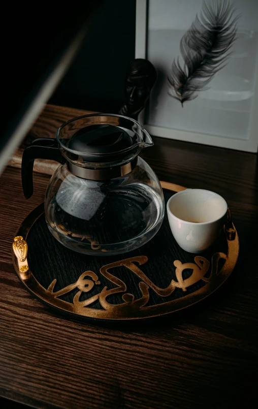 two coffee cups in a fancy glass bowl next to a tea pot