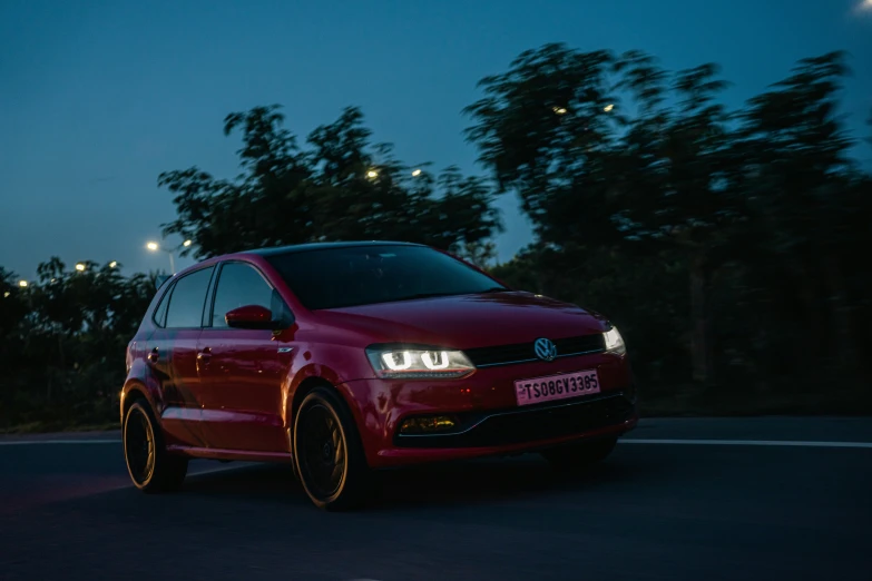 a red volkswagen is parked on a street at night