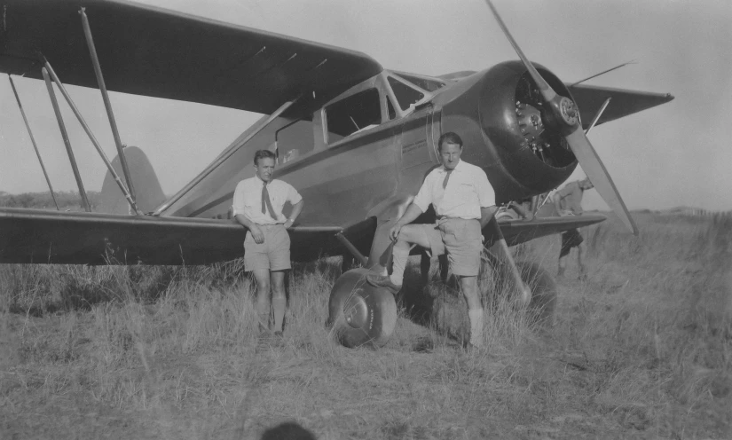 two men are standing next to an airplane