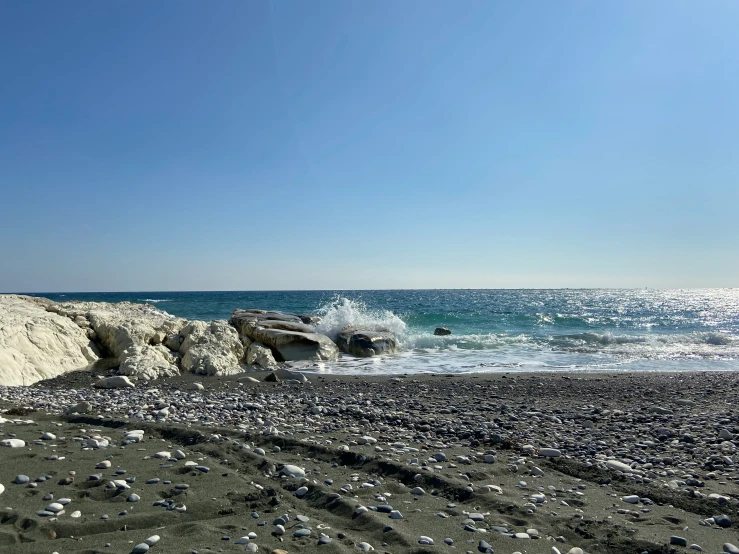 a beach with rocks and some water in the background