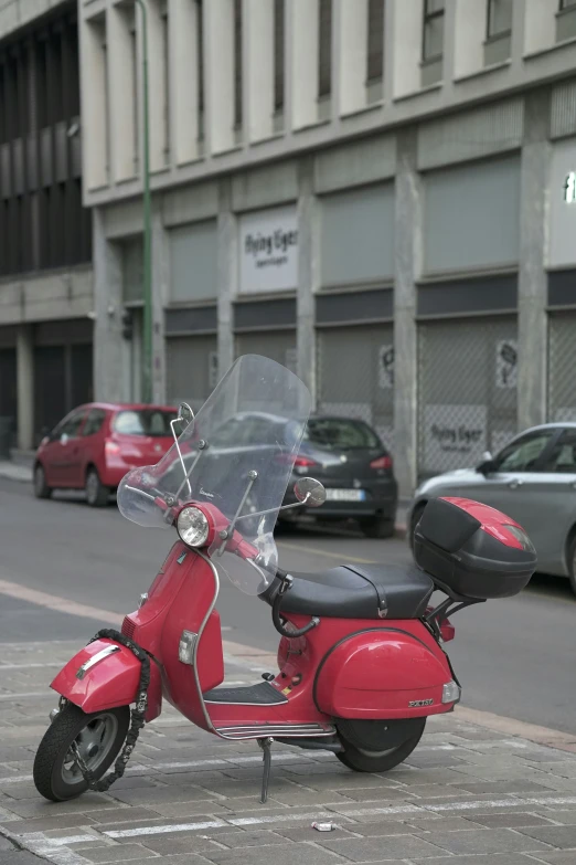 a red motor scooter is parked in front of a car