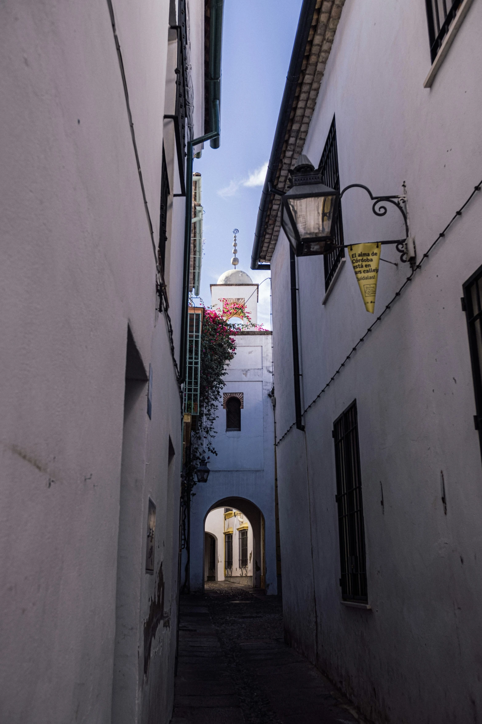 a narrow street with a light hanging over it