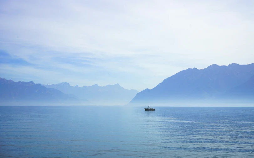 a small boat traveling on water with mountains in the background