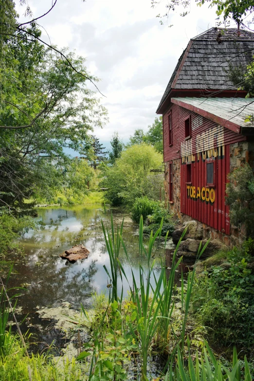 a red barn sitting on the side of a river