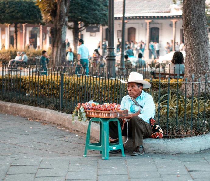 an old man is sitting on the street, selling items