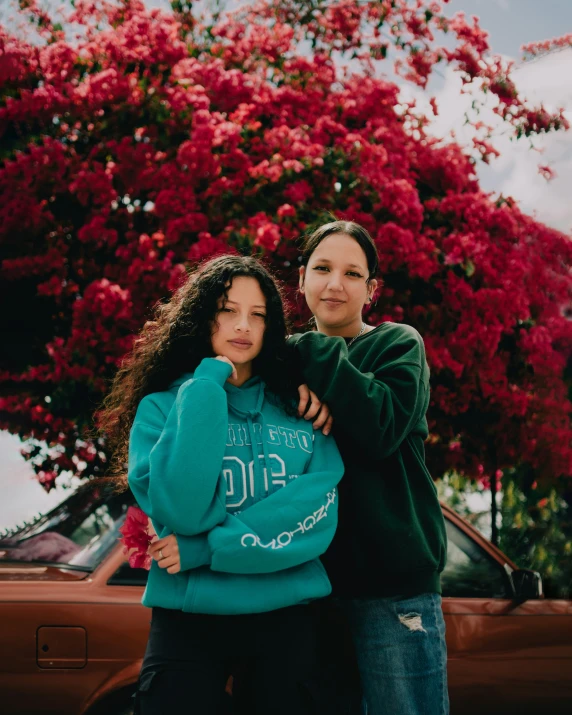 two girls hugging each other near a tree