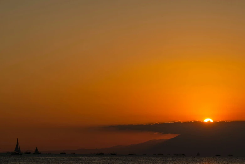 a boat is sailing in the water with the sun rising above the clouds