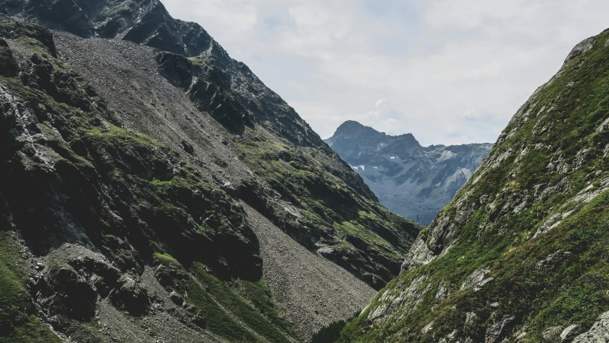 mountains side by side, with rocks in the foreground and plants growing on the sides