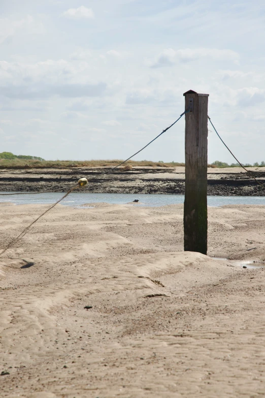 a wooden post is in the sand at a harbor